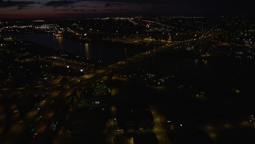 Nighttime aerial view of Downtown Portland Oregon with the Fremont Bridge and vehicles approaching on I-405 at a partly cloudy night
