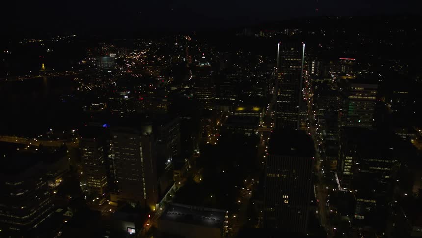 Approaching Downtown Portland's high-rise cityscape at night the aerial footage pans to reveal the iconic Hawthorne and Marquam Bridges over the Willamette River