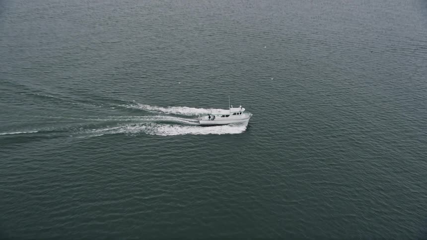 Aerial footage tracking a fishing boat sailing on the Columbia River near Cape Disappointment Washington on a cloudy day
