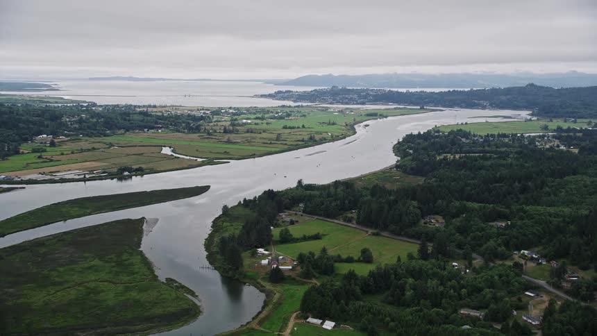Aerial footage of the Youngs River in Astoria Oregon showcasing farm fields by the water