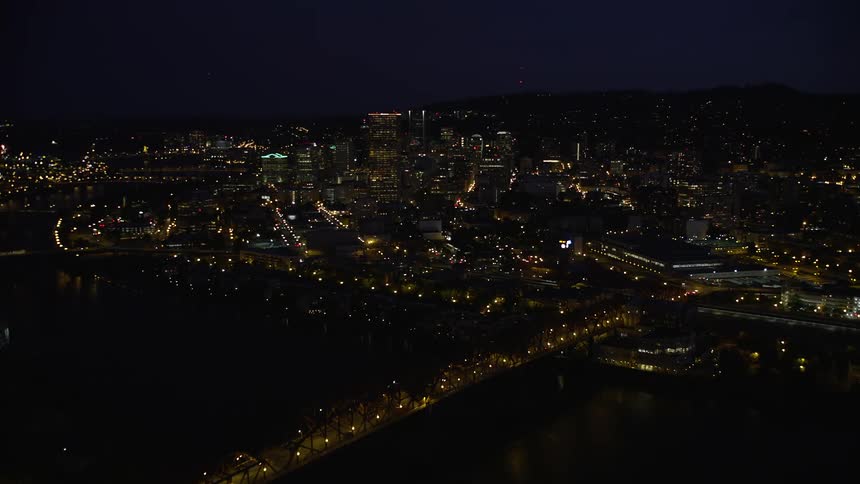 Aerial footage of downtown Portland at night showing the illuminated city skyline the Willamette River and the Broadway Bridge