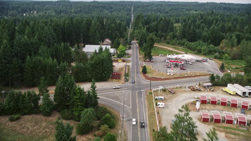 Aerial footage of a scenic drive along Wright Bliss Road passing through Gig Harbor Washington and soaring over a lush evergreen forest with power lines in view