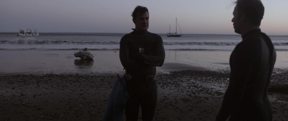 Two men are talking near a raft on the beach