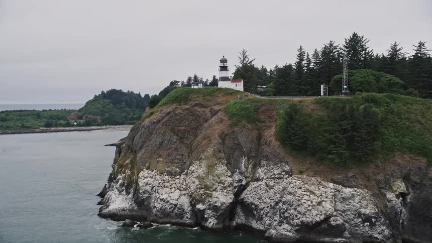 Approaching the Cape Disappointment Light a majestic lighthouse perched on a scenic coastal cliff in Washington while capturing the stunning views of the surrounding shoreline and tranquil rural setting