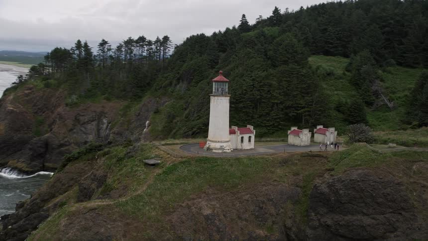 Aerial footage of the North Head Light on top of a cliff overlooking the ocean in Ilwaco Washington during the summer