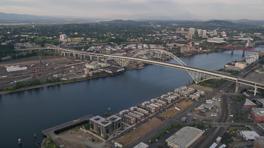 Aerial footage of the Fremont Bridge spanning the Willamette River in downtown Portland Oregon at sunset during the summer