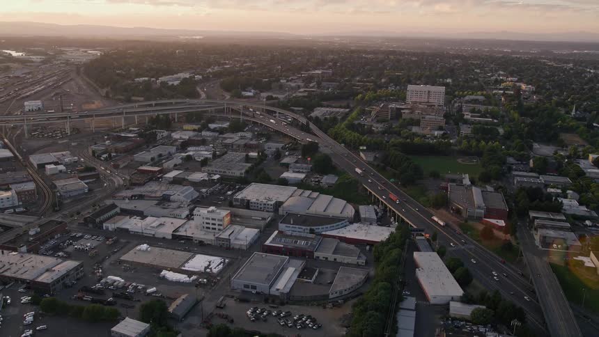 Aerial footage of the Highway 30 / Interstate 5 interchange and warehouse buildings in North Portland Oregon during sunset with light traffic and partly cloudy skies