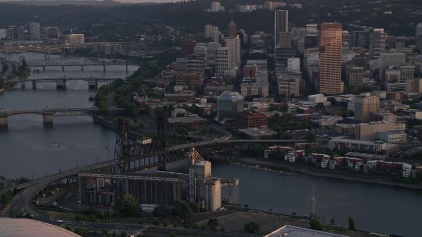 Aerial view of Portland Oregon at sunset showcasing the Rose Garden Arena Memorial Coliseum and the city's downtown area with five bridges spanning across the river