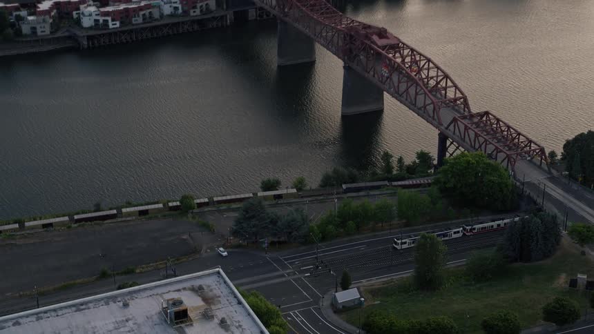 Aerial footage capturing the approaching Broadway Bridge in North Portland Oregon during sunset with a commuter train being tracked across the bridge