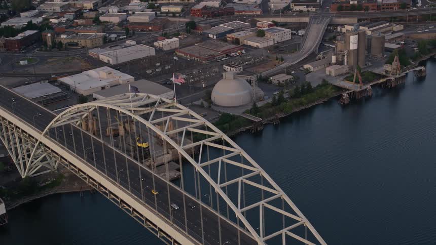 Aerial footage at sunset of the Fremont Bridge in Downtown Portland Oregon with an American flag waving in the wind