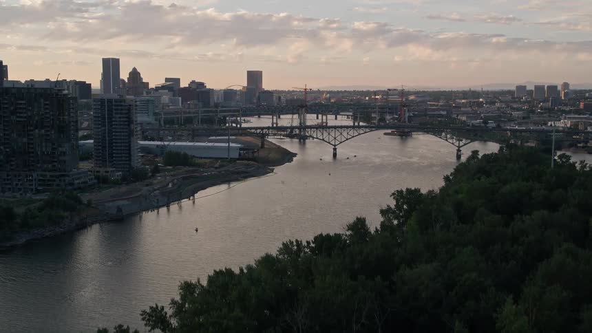 Aerial footage of Downtown Portland Oregon during sunset showcasing the Willamette River bridges and cityscape from a high vantage point
