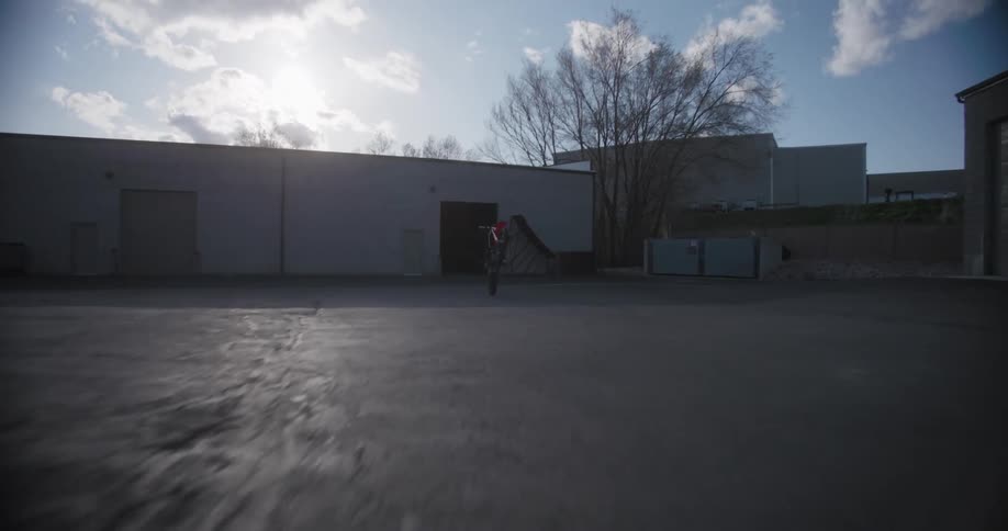 Man takes a motorcycle out of a storage unit doing a wheelie