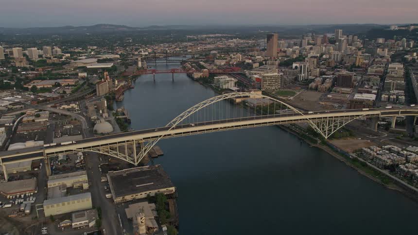 Pan across the Fremont Bridge in Downtown Portland Oregon at twilight revealing the city's high-rise buildings transportation network and the scenic Willamette River