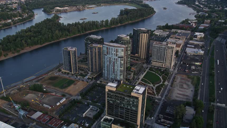 Aerial footage of South Waterfront Portland Oregon at sunset showcasing the high-rise buildings and residential neighborhoods as it approaches the city river