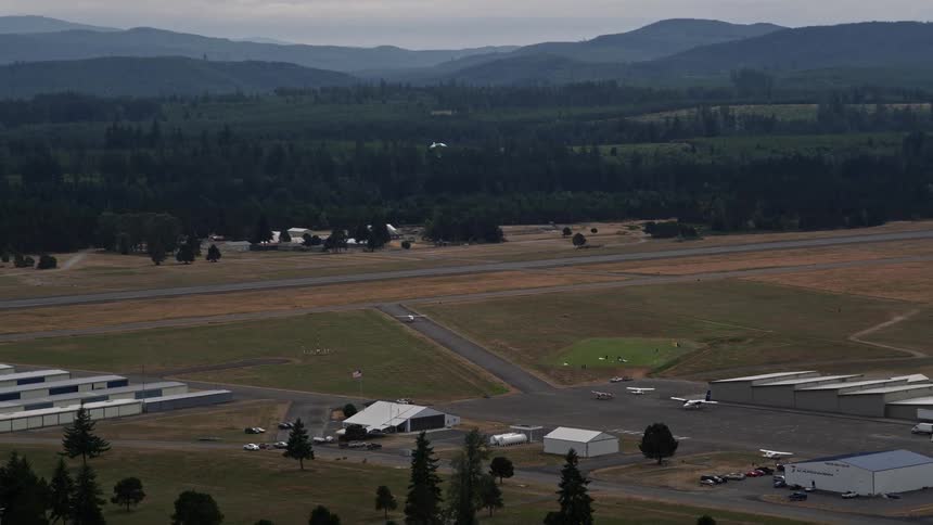 A skydiver gracefully lands on an airfield near the mountains in Washington during a sunny day