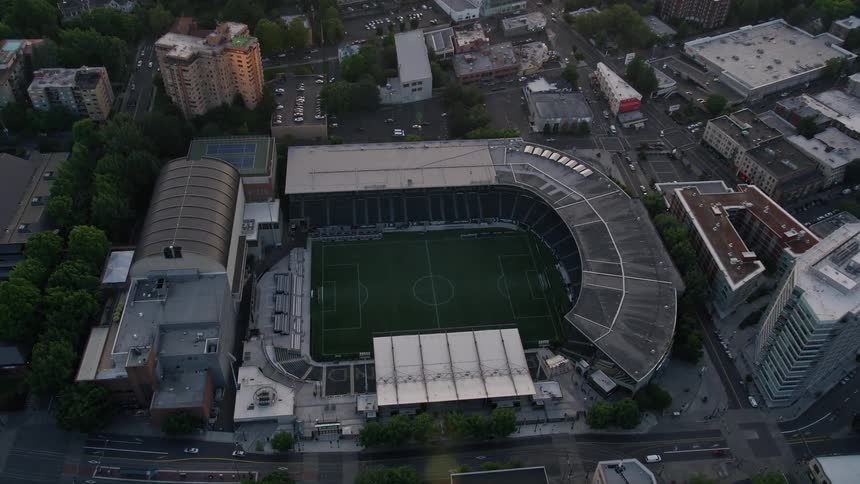 Aerial view of Providence Park soccer stadium in downtown Portland Oregon as the sun sets over the city skyline during summer