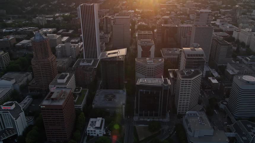 Aerial footage of downtown Portland Oregon at sunset capturing the scenic Hawthorne Bridge and Willamette River as the camera follows their path through the city