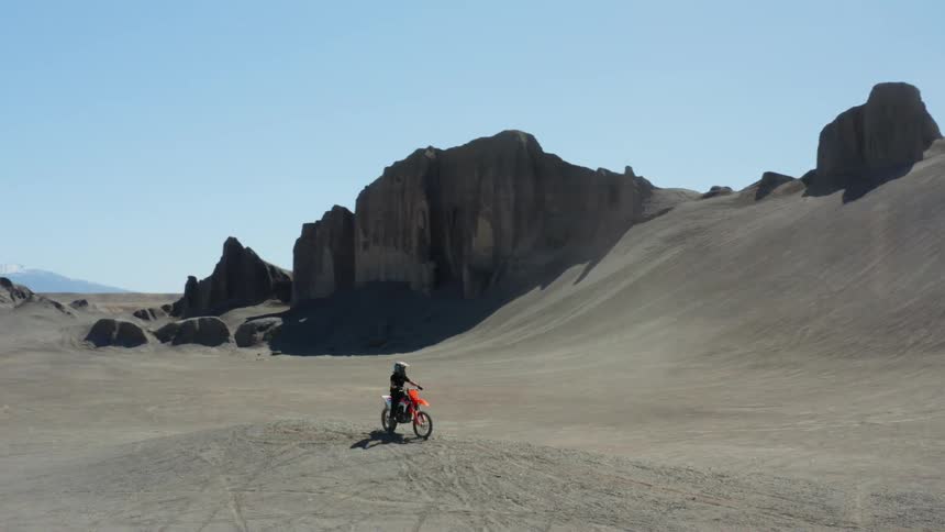 Man sits on a motorcycle alone in a desert area on a sunny day