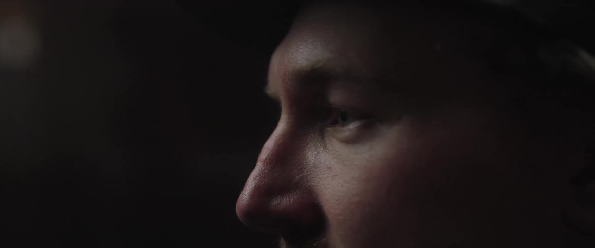 A man looking sad as he continue to stair in a dark environment