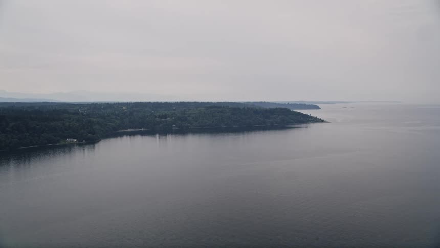 Aerial view of Vashon Island and Puget Sound Washington as the camera flies away from the island showcasing the ocean forest and shoreline
