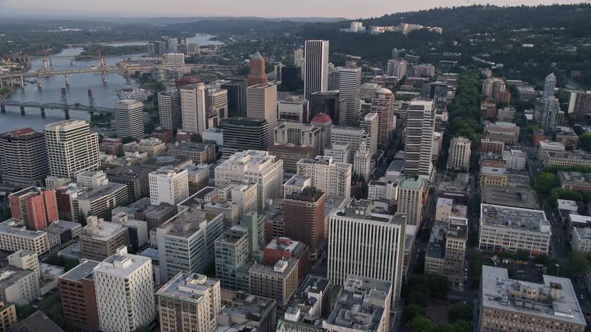Approaching Oregon Science and Health University at sunset this aerial footage showcases the high-rise buildings of downtown Portland Oregon as well as the city's vibrant atmosphere