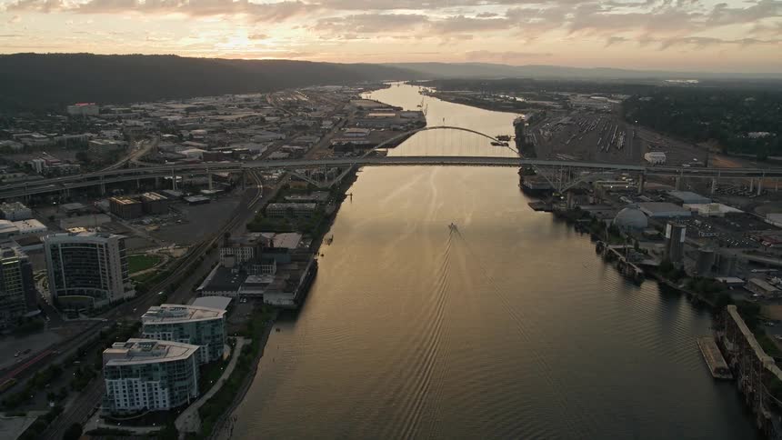 Approaching the Fremont Bridge over the Willamette River at twilight capturing the beauty of Downtown Portland Oregon as the city is split by the river connected by bridges adorned with highrises under partly cloudy skies during the summer