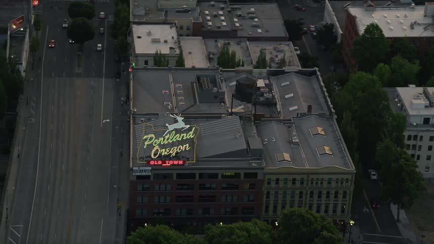Aerial footage tracking the iconic White Stag Sign in downtown Portland Oregon during twilight showcasing the historical landmark and bustling metropolis