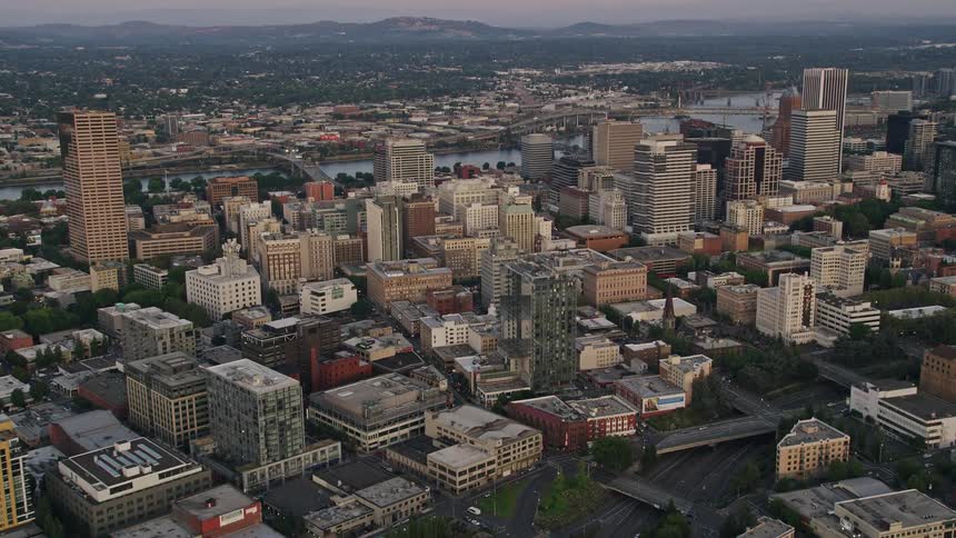 Fly over downtown Portland Oregon during sunset pan right to capture the breathtaking views of the KOIN Center and Wells Fargo Center as well as the city's iconic river and bridges