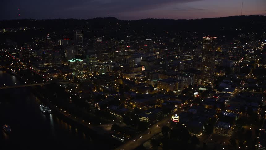 A mesmerizing twilight view of downtown Portland Oregon with towering skyscrapers the Steel and Burnside Street Bridges and the tranquil waters of the Willamette River