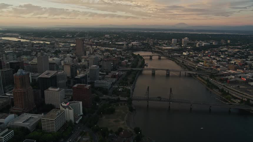 Flying over the Willamette River at twilight this aerial footage showcases the beautiful high-rise buildings and bridges of downtown Portland Oregon