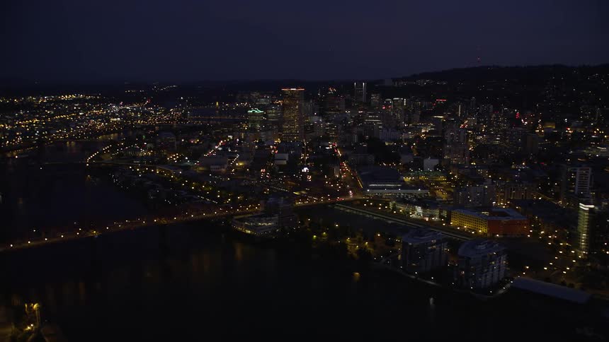 Aerial footage of the Fremont Bridge orbiting revealing Downtown Portland Oregon during twilight with the Willamette River in view