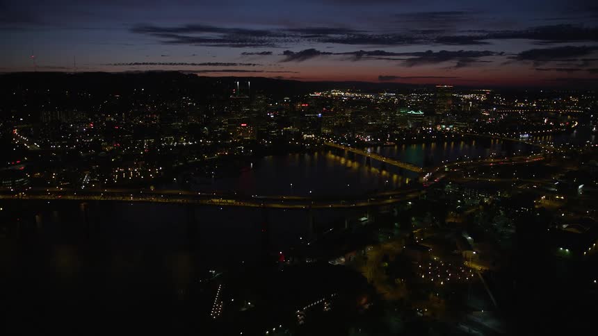  aerial footage of flying over Marquam Bridge approaching Downtown Portland Oregon during twilight showcasing high rise buildings city river and the beautiful natural surroundings
