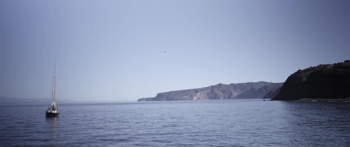 A boat is in the water with it's sails down