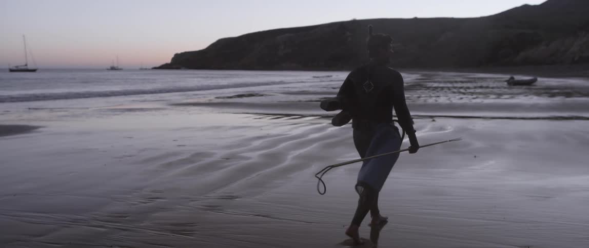 A man walks along the beach in scuba gear