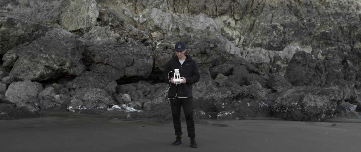 A man is holding a device on a beach