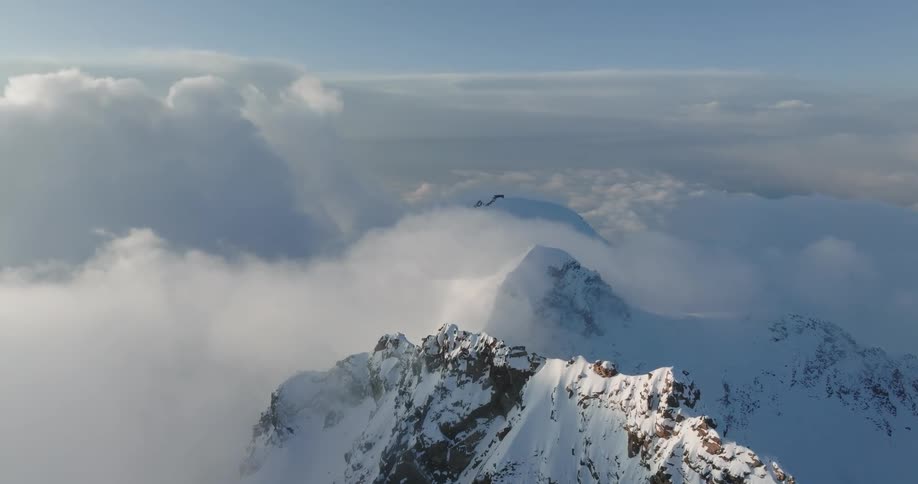Clouds partially cover snowy mountain tops