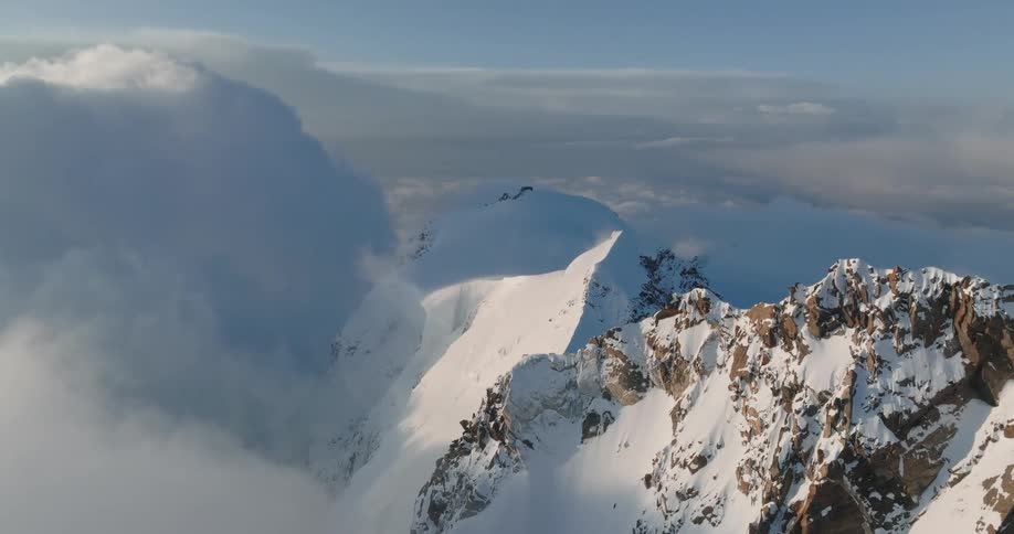 Aerial view of mountains at cloud level covered in snow