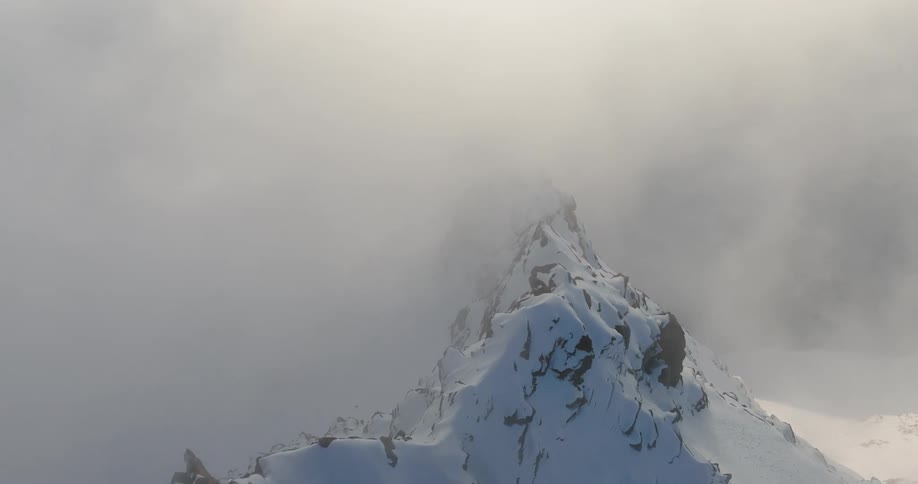 Aerial view of mountains at cloud level covered in snow