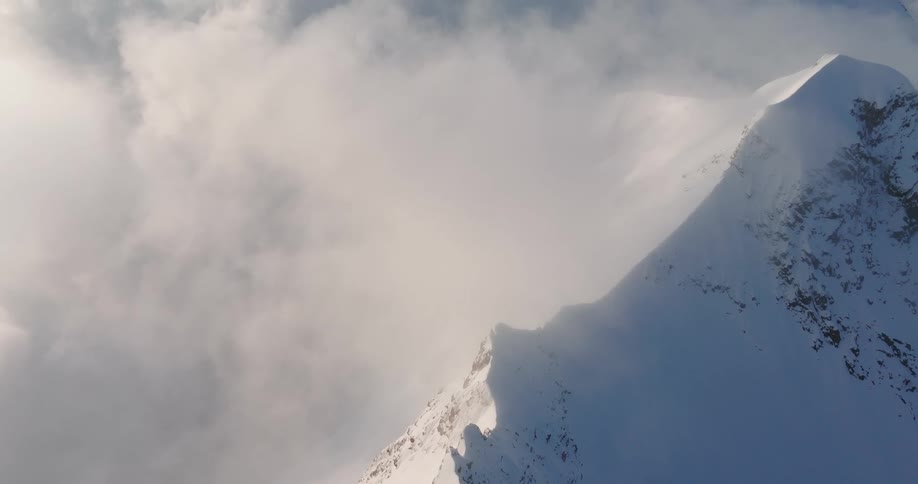 Aerial view of mountains at cloud level covered in snow