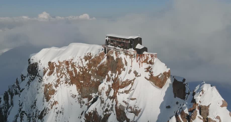 A wooden house on top of a snowcovered mountain