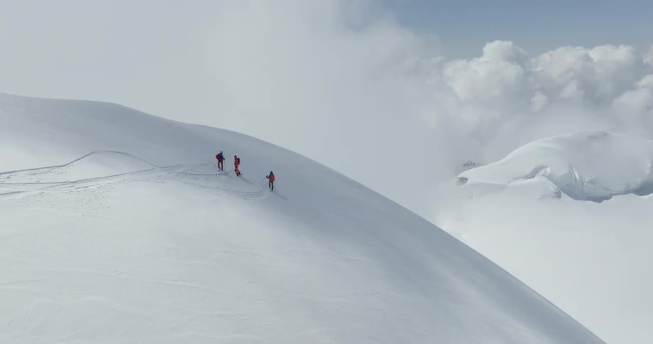 Three people hiking on a snowcovered mountain at cloud level
