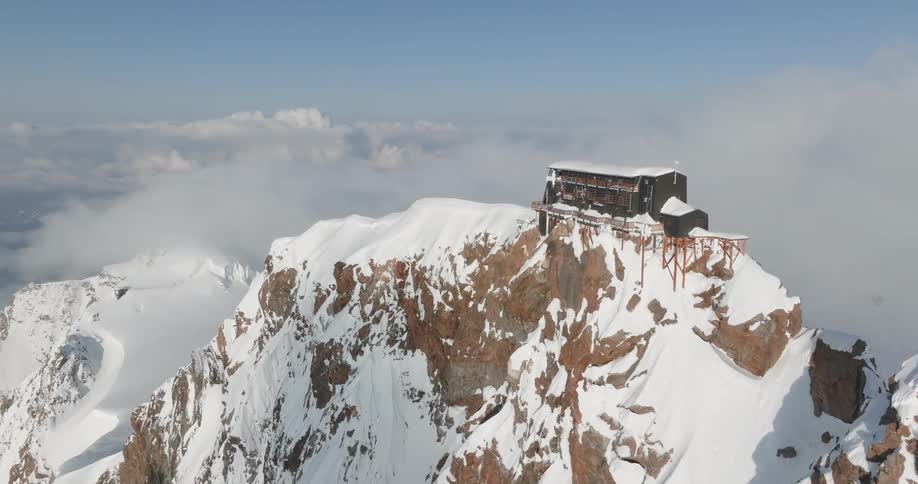 Aerial view of a snowcovered mountain with a building on the summit