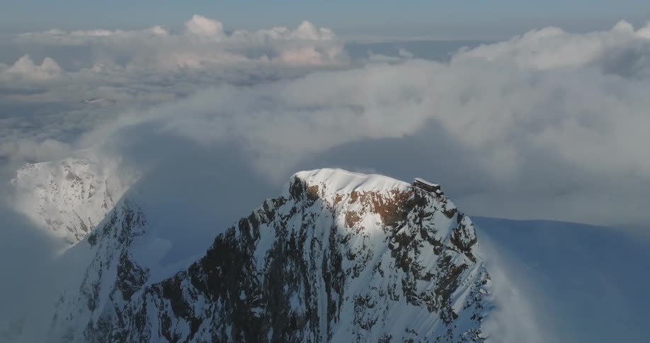 Aerial view of mountains at cloud level covered in snow