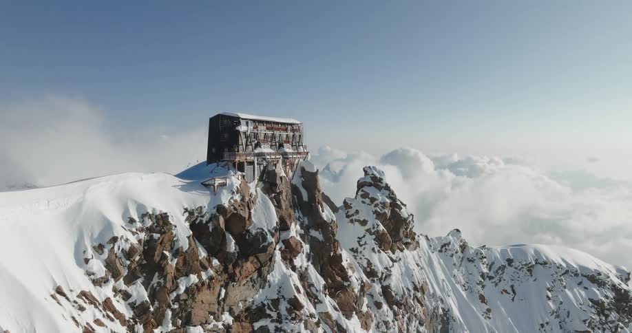 A dark wooden house on top of an icy mountain