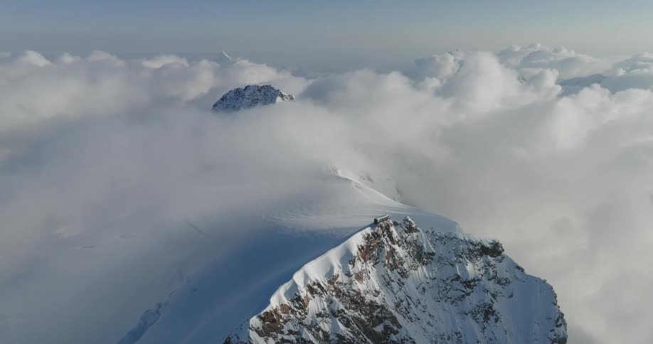 Aerial view of a mountain at cloud level covered in snow