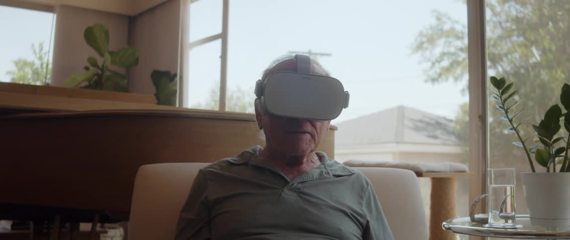 An elderly person sitting on a sofa using virtual reality glasses