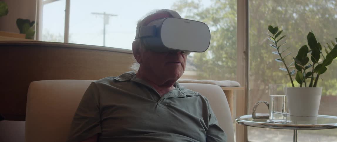 A gentleman with virtual reality glasses is sitting on the sofa