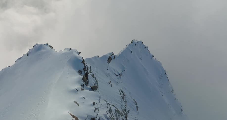 In the artic a snow filled mountain with the area surrounded with fog