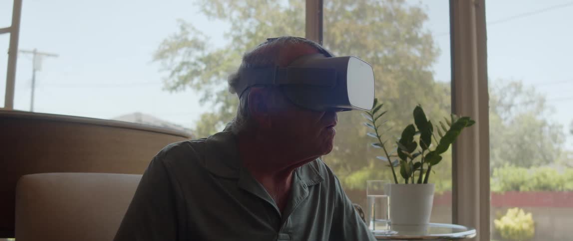 Elderly person sitting in an armchair using virtual reality glasses