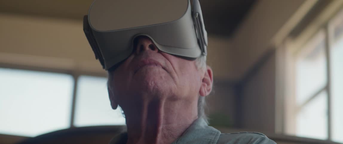 An elderly man wearing a VR headset looking surprised